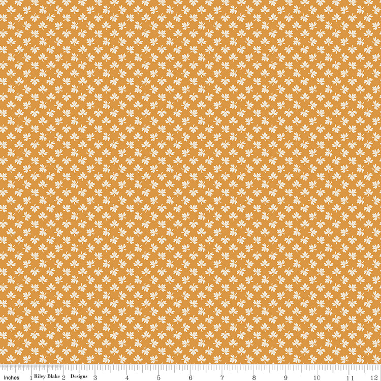 A repeating pattern of small white and muted gold plus signs on a dusty pink background, with a ruler along the bottom edge showing scale. 