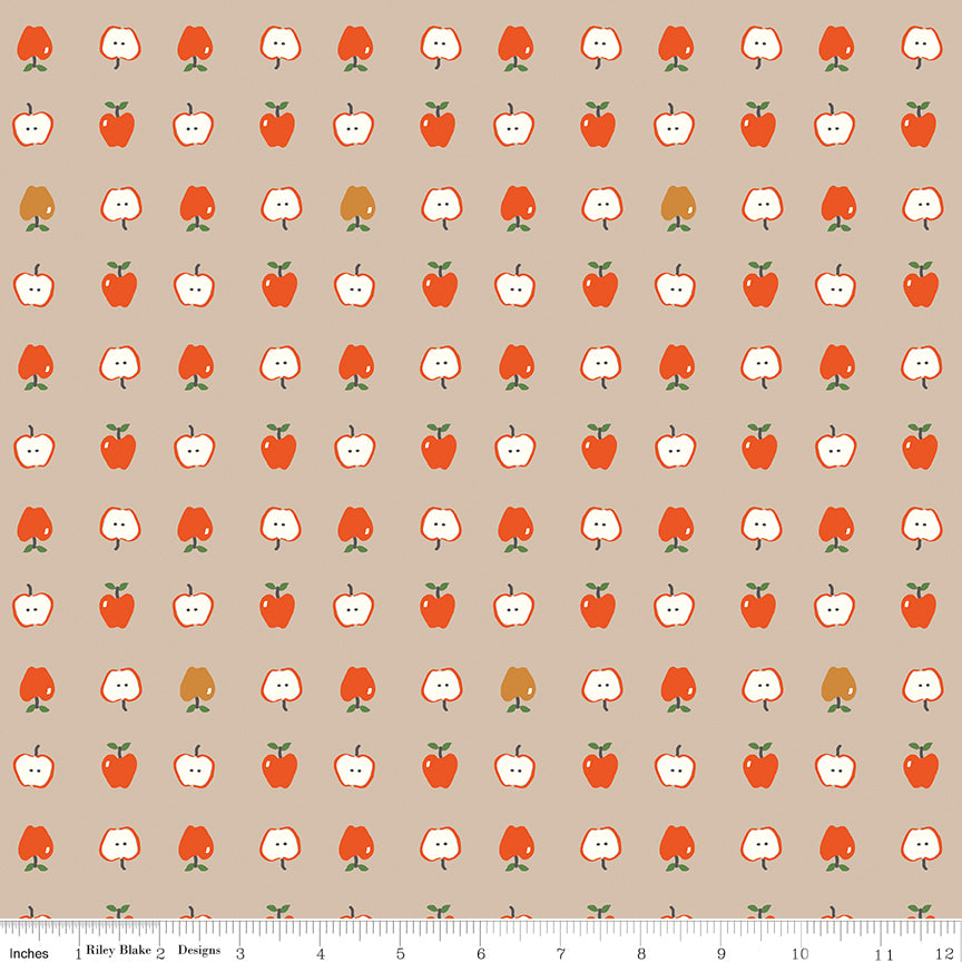 Cotton Nook Apples Biscuit fabric with red apples and sliced apples on a warm beige background with ruler for scale.