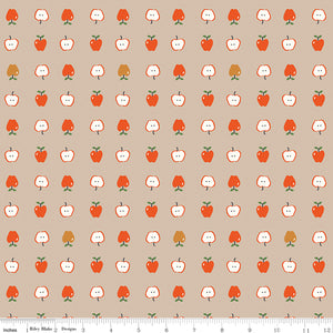 Cotton Nook Apples Biscuit fabric with red apples and sliced apples on a warm beige background with ruler for scale.