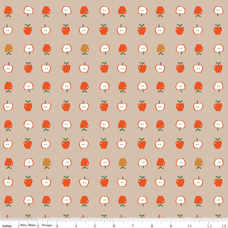 Cotton Nook Apples Biscuit fabric with red apples and sliced apples on a warm beige background with ruler for scale.