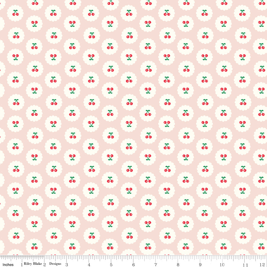 Cotton Nook Cherries Blush fabric with red cherries inside white scalloped circles on pale pink with ruler for scale.