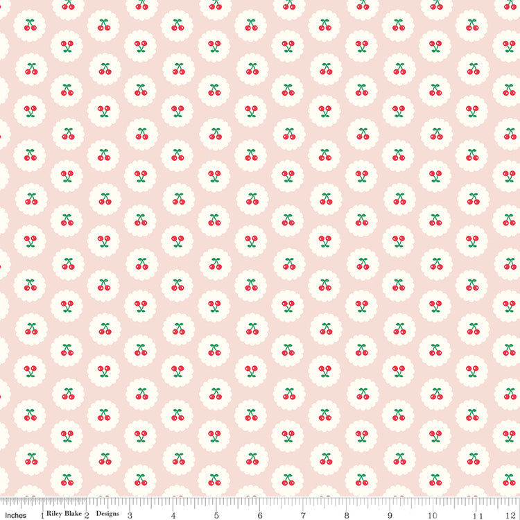 Cotton Nook Cherries Blush fabric with red cherries inside white scalloped circles on pale pink with ruler for scale.