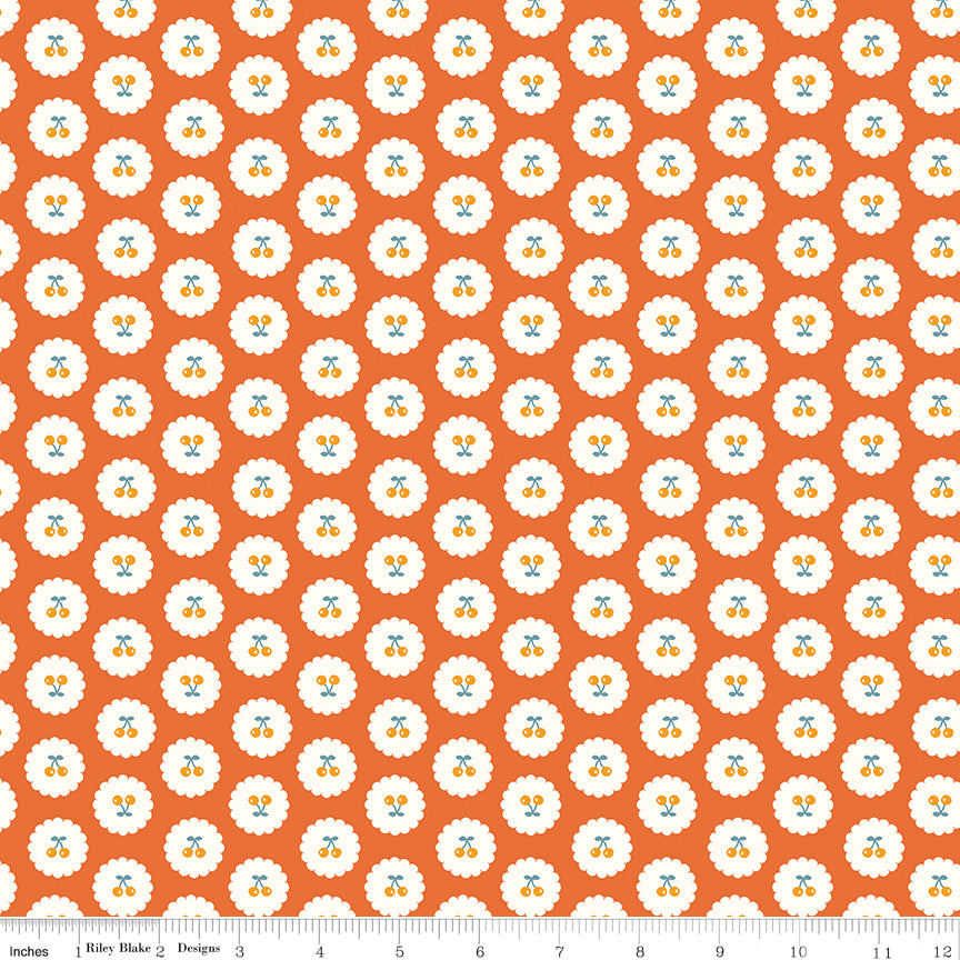 Cotton Nook Cherries Orange fabric with golden cherries in white scalloped circles on orange with ruler for scale.