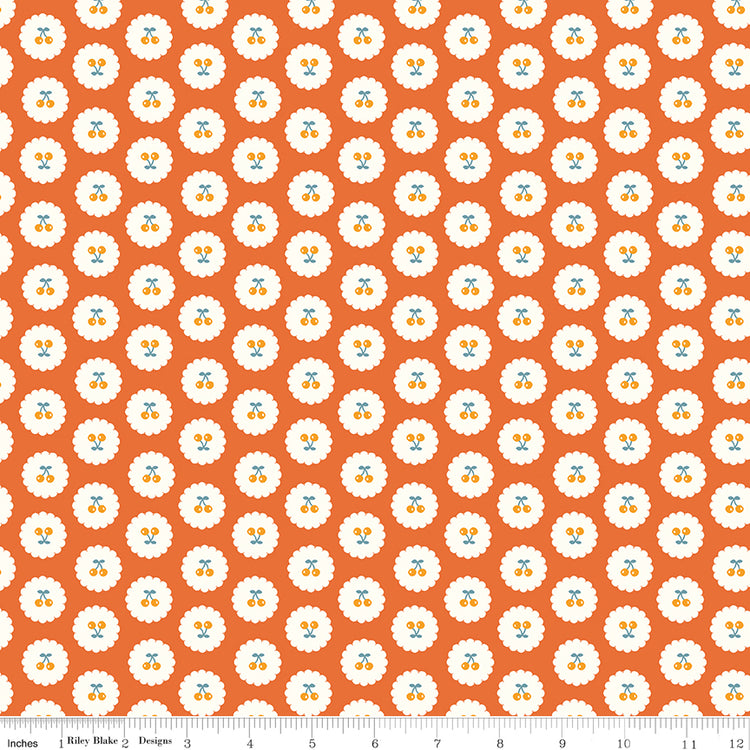 Cotton Nook Cherries Orange fabric with golden cherries in white scalloped circles on orange with ruler for scale.