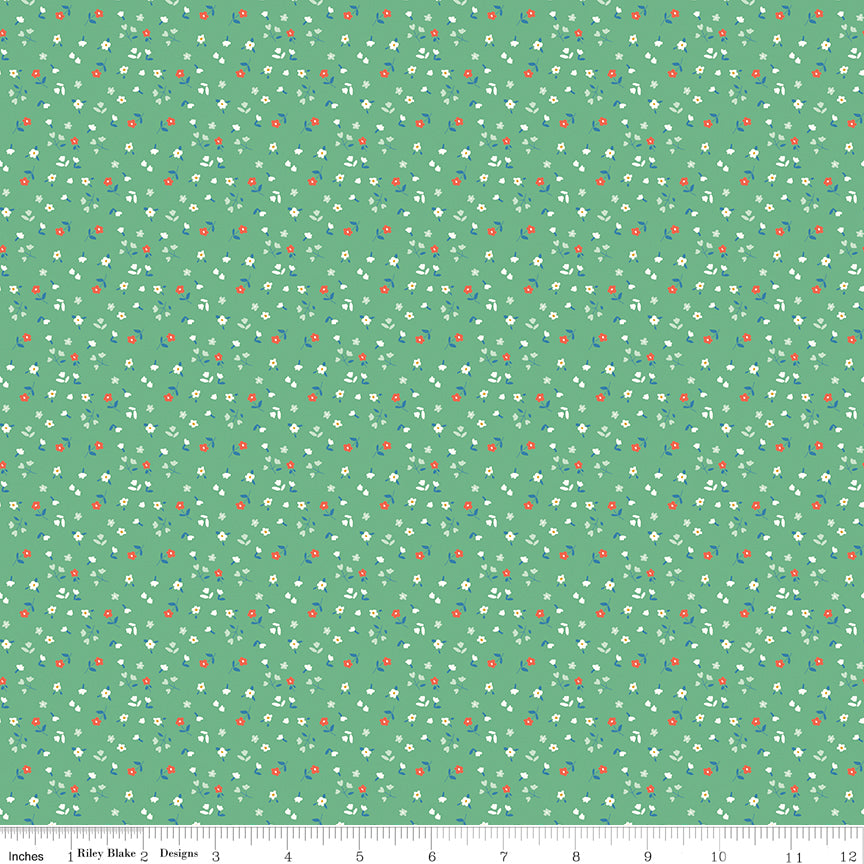 Cotton Nook Flowers Green fabric with tiny white, coral and blue flowers on a green background with ruler for scale.