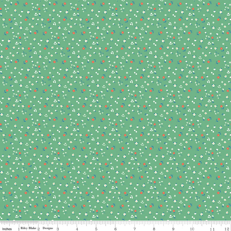 Cotton Nook Flowers Green fabric with tiny white, coral and blue flowers on a green background with ruler for scale.