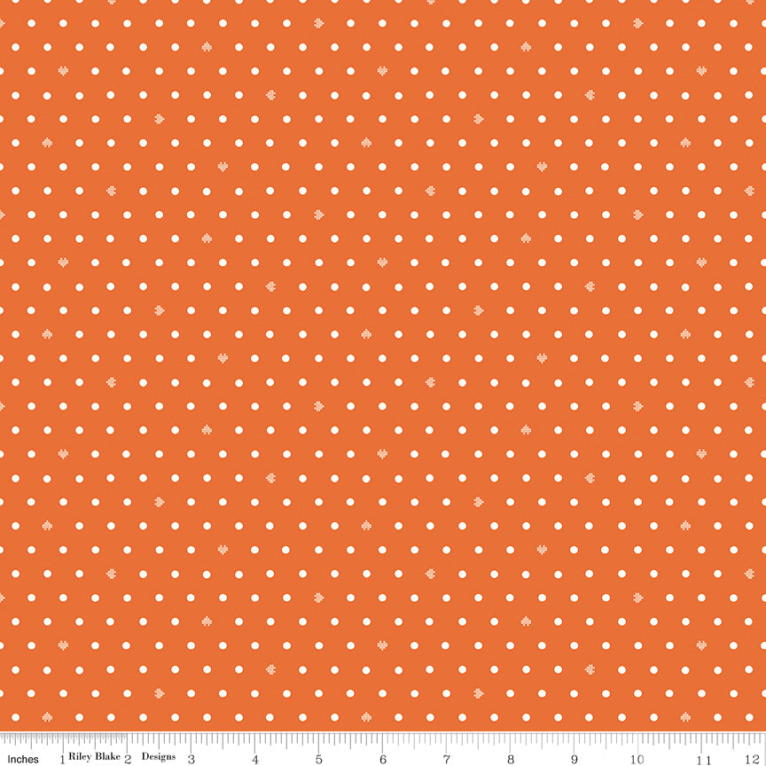 Cotton Nook Dots Orange fabric with small cream dots scattered across a bright orange background with ruler for scale.