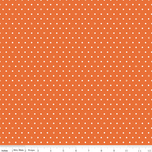 Cotton Nook Dots Orange fabric with small cream dots scattered across a bright orange background with ruler for scale.