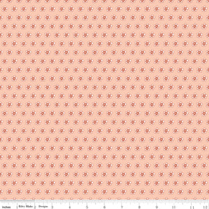 Blush pink fabric with evenly spaced small cream and coral flowers with a ruler for scale