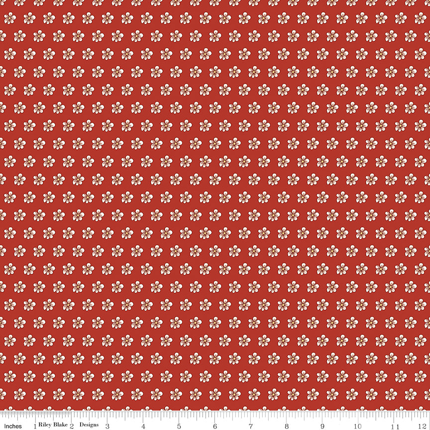 Red fabric with evenly spaced small cream flowers and a ruler for scale. 