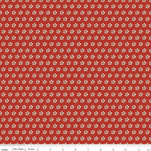Red fabric with evenly spaced small cream flowers and a ruler for scale. 