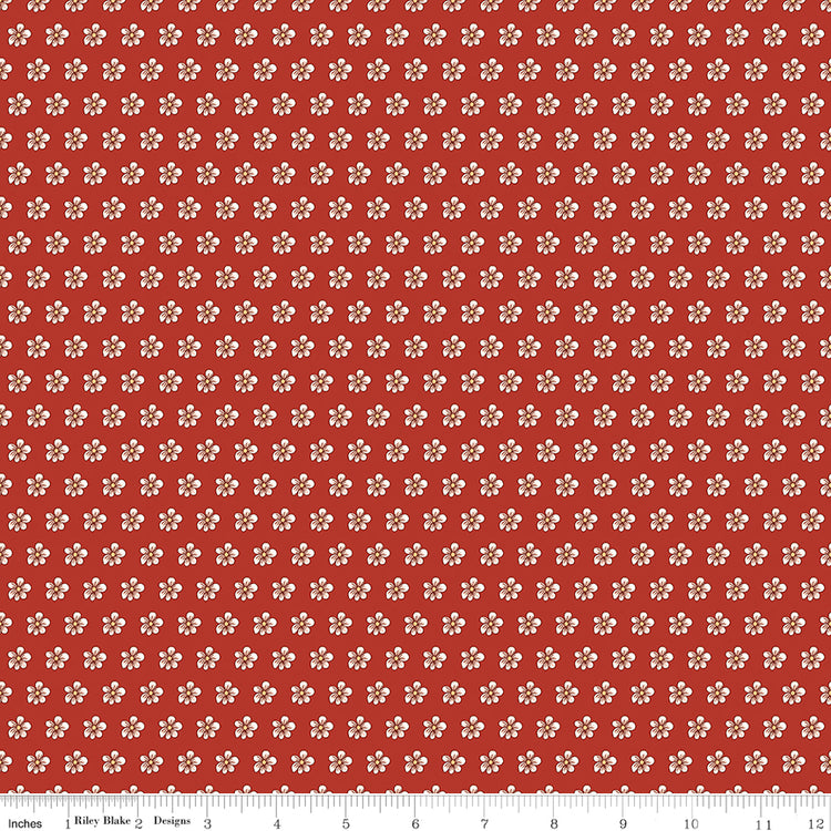 Red fabric with evenly spaced small cream flowers and a ruler for scale. 