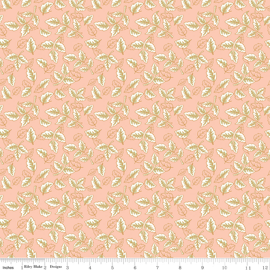Blush pink fabric with scattered cream and sage green leafy sprigs with a ruler along the bottom for scale. 