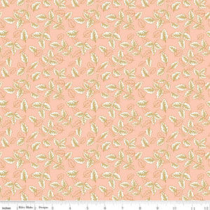 Blush pink fabric with scattered cream and sage green leafy sprigs with a ruler along the bottom for scale. 