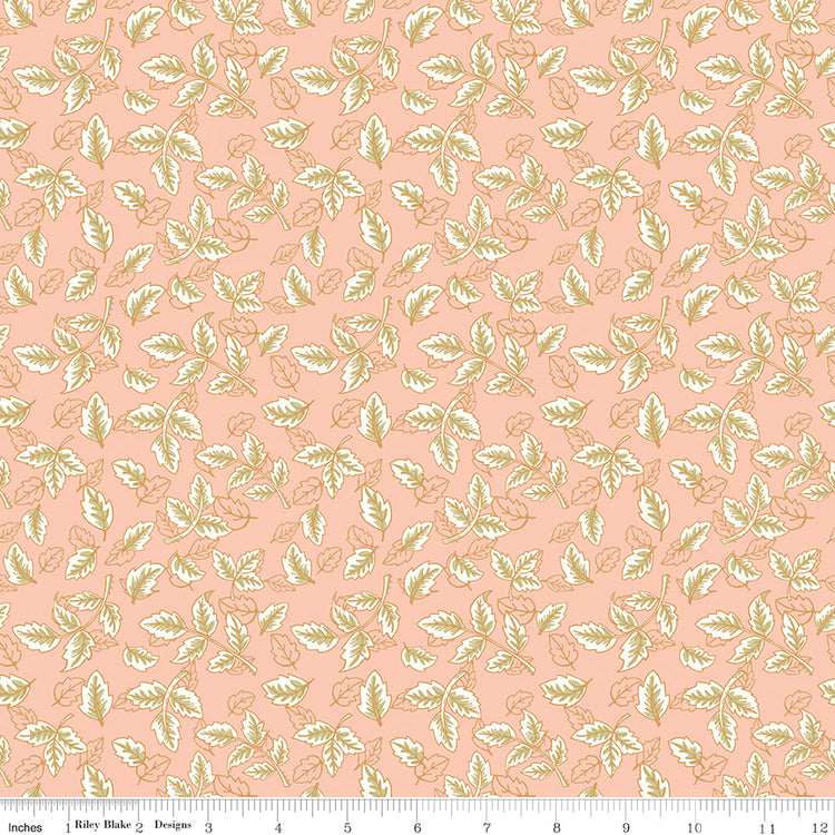 Blush pink fabric with scattered cream and sage green leafy sprigs with a ruler along the bottom for scale. 