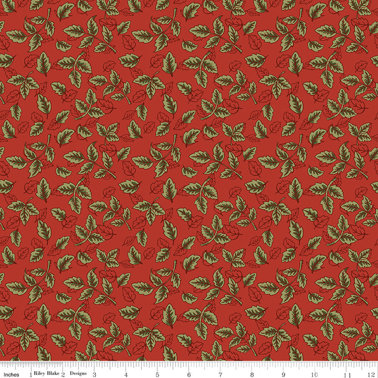 Red fabric with scattered olive green leafy sprigs and a ruler for scale