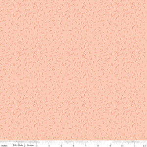 Blush pink fabric with scattered tiny coral leaf motifs and a ruler for scale along the bottom. 