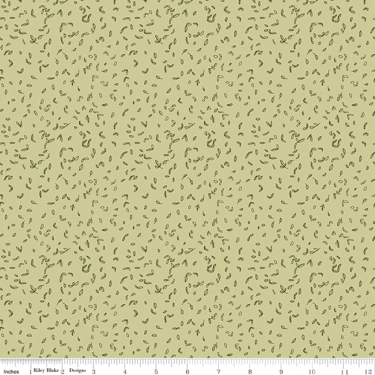 Celery green fabric with scattered tiny dark green leaf motifs with a ruler for scale along the bottom. 
