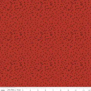 Red fabric with scattered tiny dark leaf motifs with ruler for scale. 