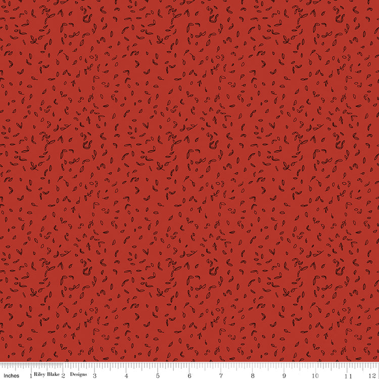 Red fabric with scattered tiny dark leaf motifs with ruler for scale. 