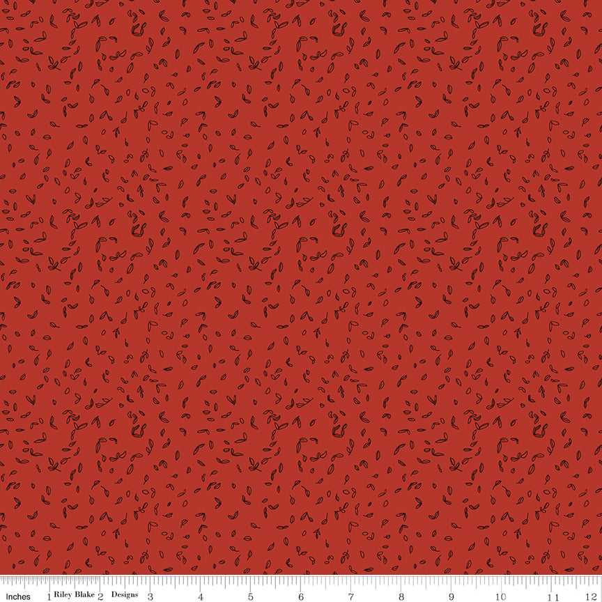 Red fabric with scattered tiny dark leaf motifs with ruler for scale. 