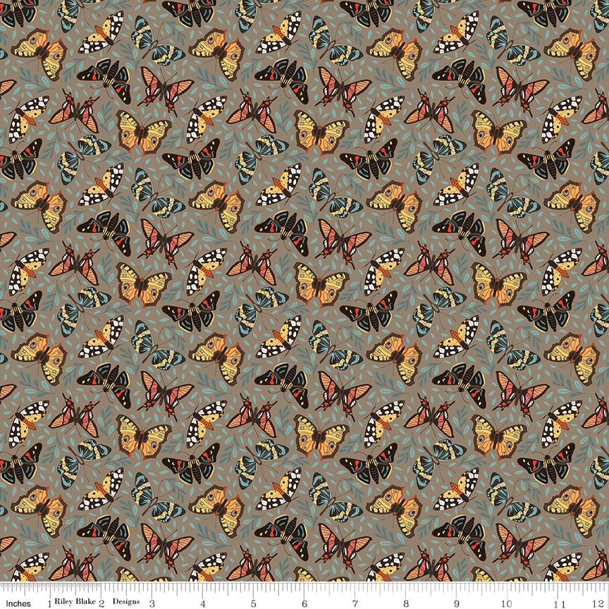 A repeating fabric pattern featuring colorful butterflies in orange, yellow, black, and blue on a muted gray-green background, with a ruler along the bottom edge showing scale.