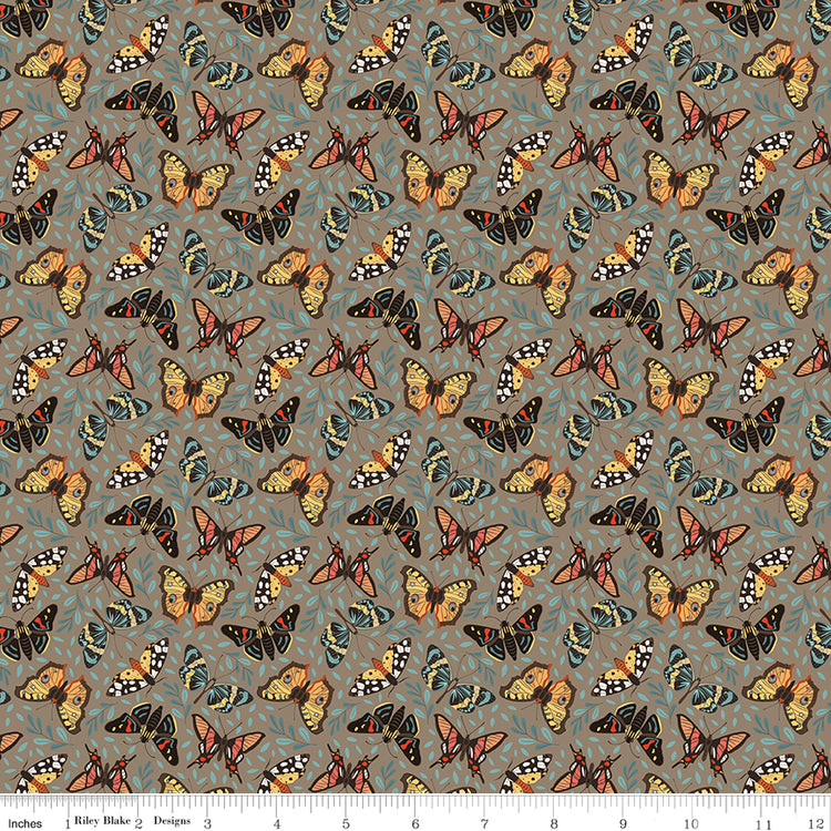 A repeating fabric pattern featuring colorful butterflies in orange, yellow, black, and blue on a muted gray-green background, with a ruler along the bottom edge showing scale.