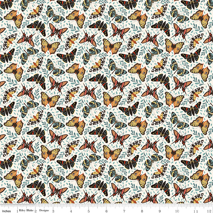 A repeating fabric pattern featuring orange, black, and yellow butterflies with blue-gray leaves on a white background, with a ruler along the bottom edge showing scale.