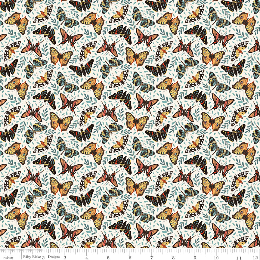 A repeating fabric pattern featuring orange, black, and yellow butterflies with blue-gray leaves on a white background, with a ruler along the bottom edge showing scale.