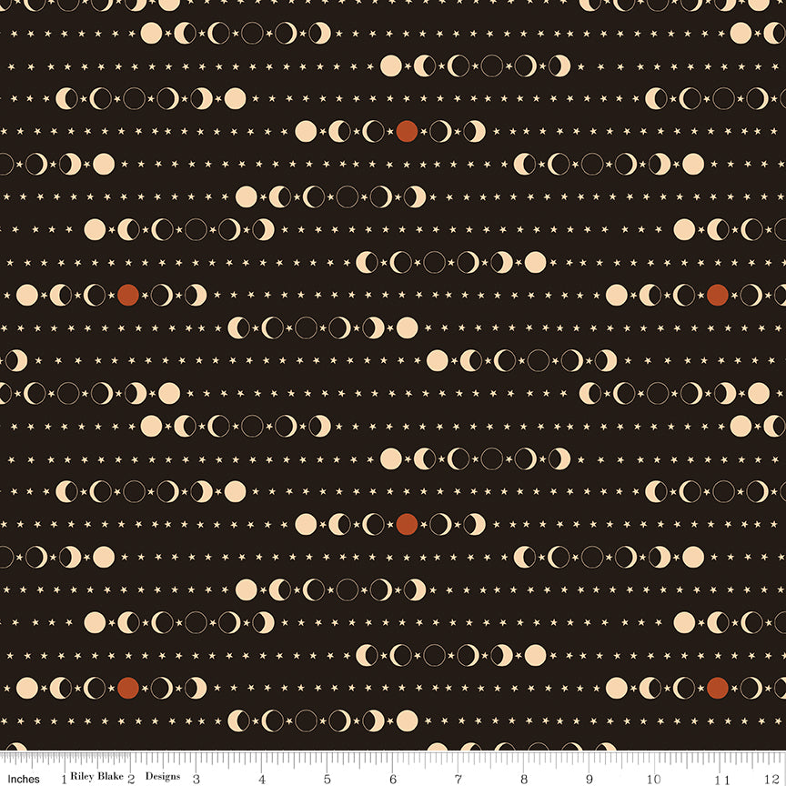 A repeating celestial pattern of moon phases, stars, and dots on a dark brown background, with a fabric ruler for scale.