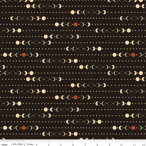 A repeating celestial pattern of moon phases, stars, and dots on a dark brown background, with a fabric ruler for scale.