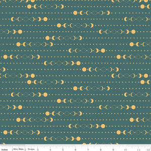 A repeating celestial pattern of sun and moon phases and small stars on a muted teal fabric background, shown with a ruler at the bottom indicating scale.