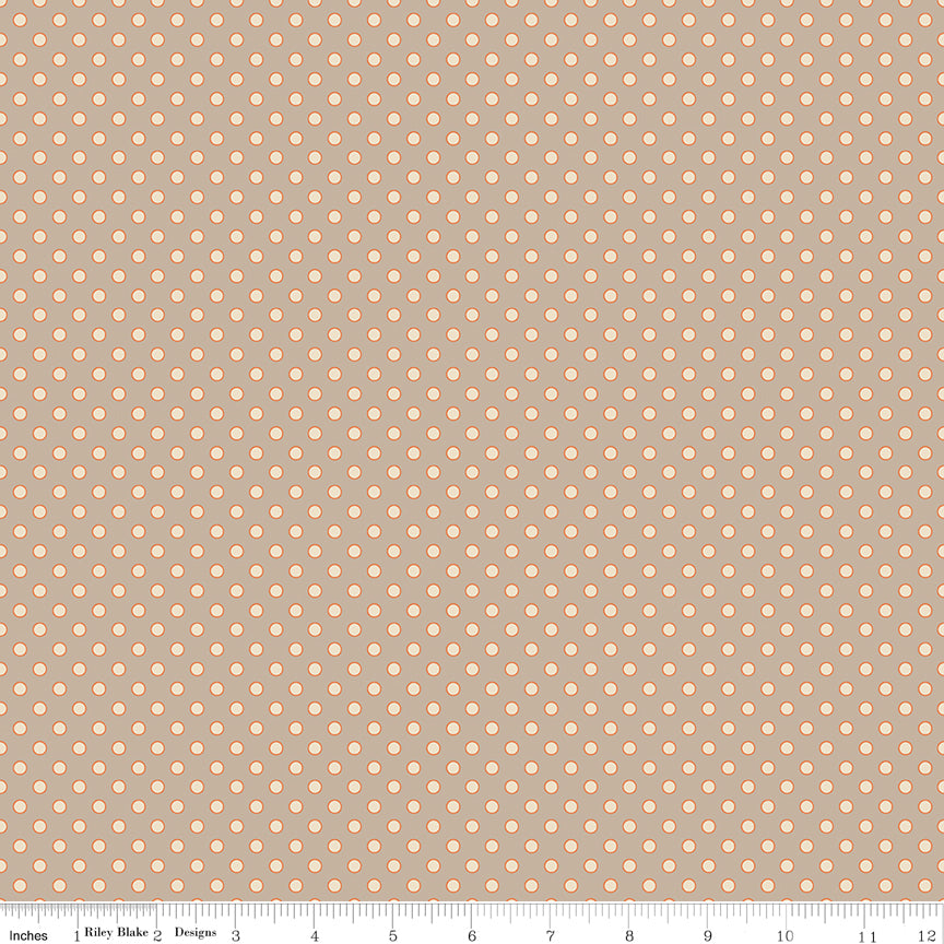 A repeating fabric pattern of small peach-colored dots on a warm taupe background, with a measuring ruler along the bottom edge showing scale.