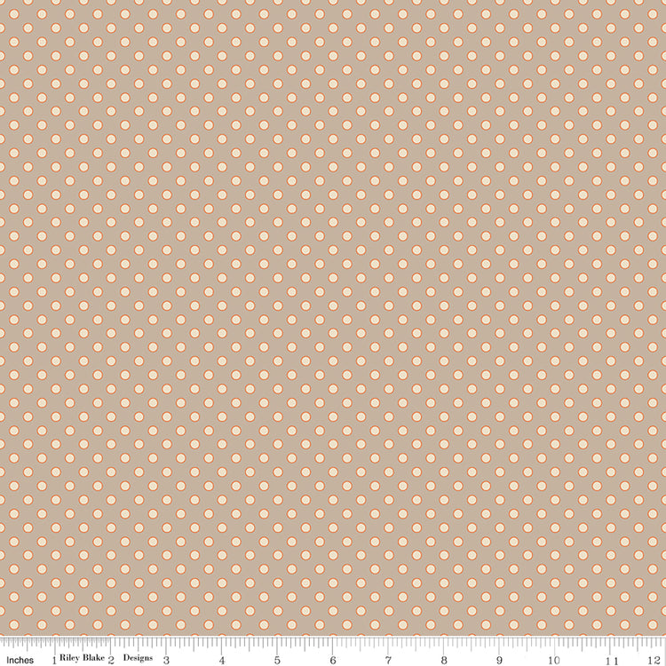 A repeating fabric pattern of small peach-colored dots on a warm taupe background, with a measuring ruler along the bottom edge showing scale.