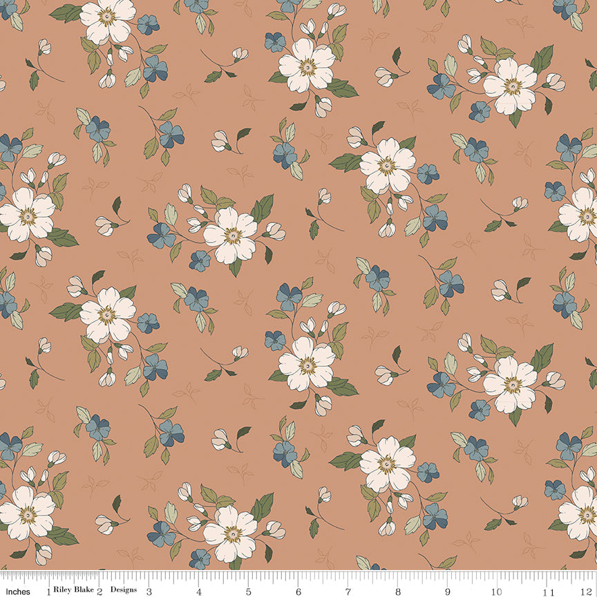 Main Light Clay fabric with cream blossoms, dusty blue flowers, and olive leaves on a warm clay background with ruler for scale.