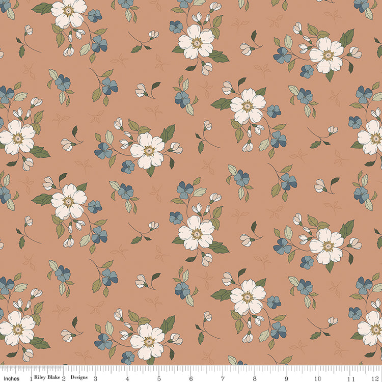 Main Light Clay fabric with cream blossoms, dusty blue flowers, and olive leaves on a warm clay background with ruler for scale.