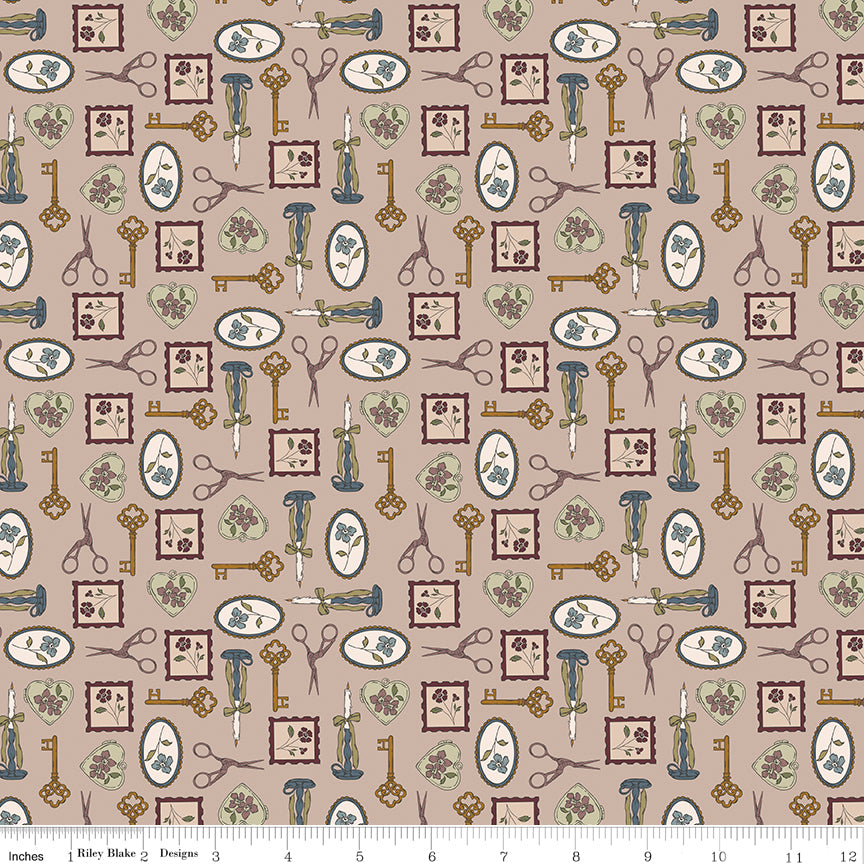 Charmed Doe fabric with keys, scissors, candlesticks, floral frames, and heart charms on rosy taupe with ruler for scale.