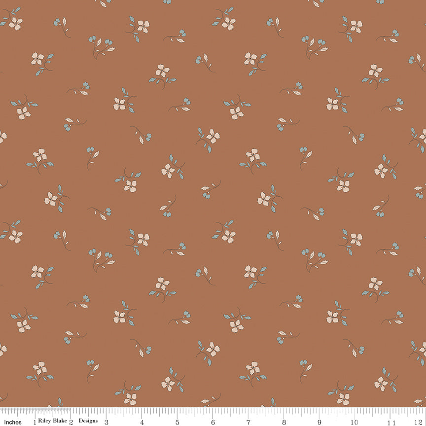 Iris Clay fabric with cream flowers, blue-gray leaves, and tiny buds scattered on warm terracotta with ruler for scale.