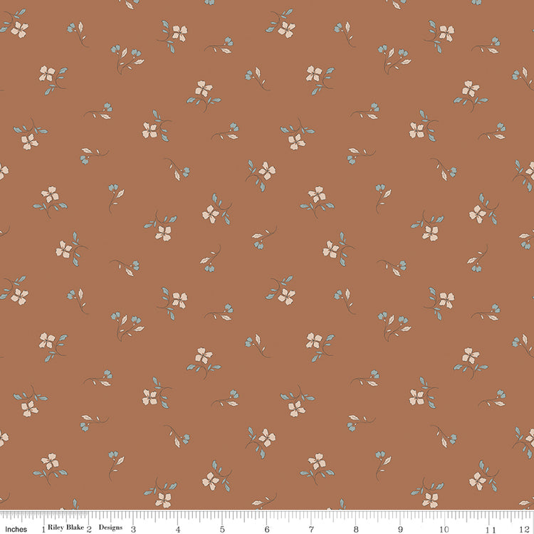Iris Clay fabric with cream flowers, blue-gray leaves, and tiny buds scattered on warm terracotta with ruler for scale.