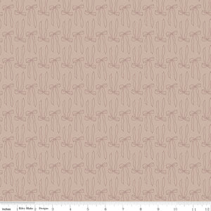 Bows Doe fabric with fine brown ribbon bow outlines and long flowing tails on rosy taupe with ruler for scale.