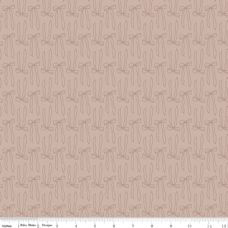 Bows Doe fabric with fine brown ribbon bow outlines and long flowing tails on rosy taupe with ruler for scale.