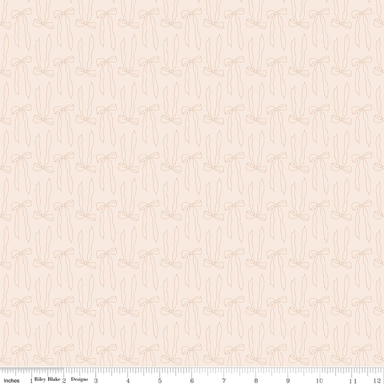 Bows Latte fabric with pale peach outlines of ribbon bows and trailing tails on creamy ivory with ruler for scale.