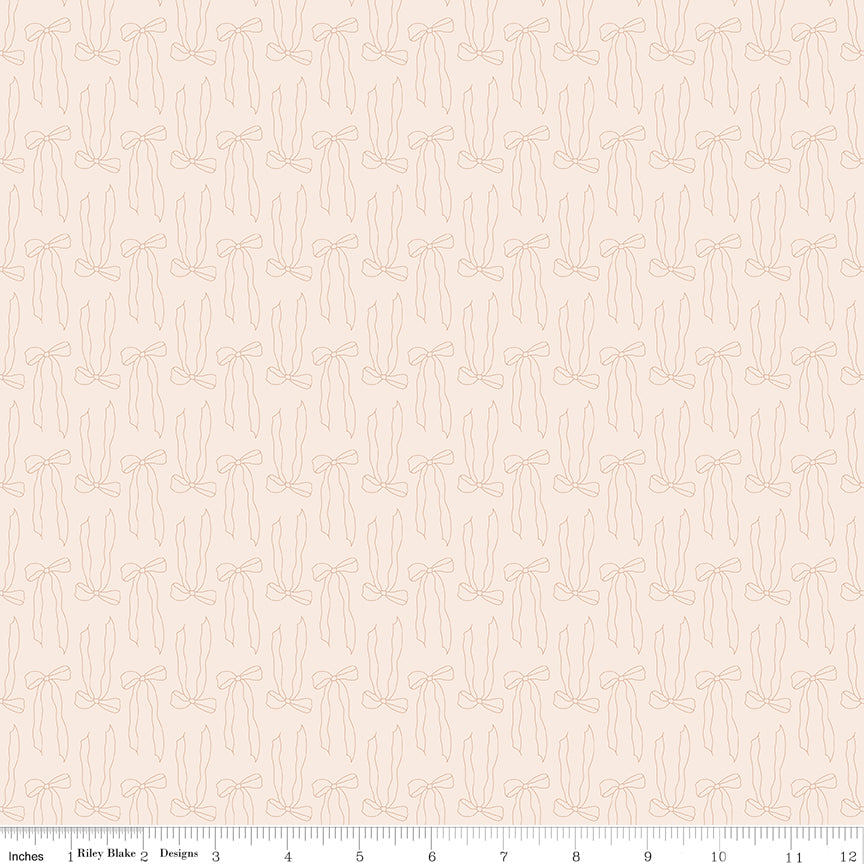 Bows Latte fabric with pale peach outlines of ribbon bows and trailing tails on creamy ivory with ruler for scale.