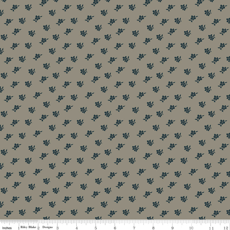 Magnolia Light Gray fabric with small charcoal-blue floral sprigs scattered across a warm gray background with ruler for scale.