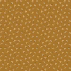 Magnolia Suede fabric with tiny pale golden flowers and leaves scattered on a caramel-brown background.