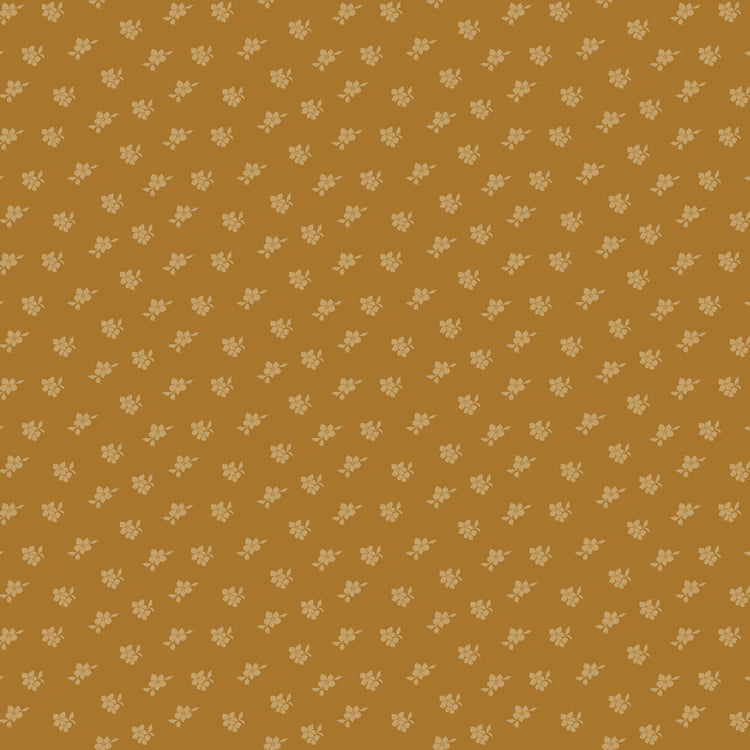 Magnolia Suede fabric with tiny pale golden flowers and leaves scattered on a caramel-brown background.