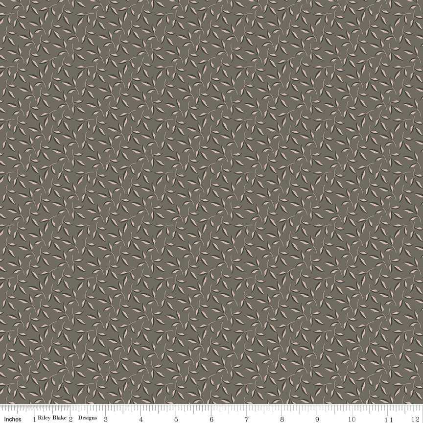 Evergreen Gray fabric with blush-beige leaves, dark gray accents, and winding stems on taupe gray with ruler for scale.
