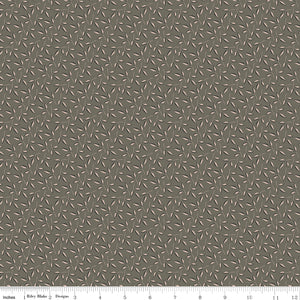 Evergreen Gray fabric with blush-beige leaves, dark gray accents, and winding stems on taupe gray with ruler for scale.
