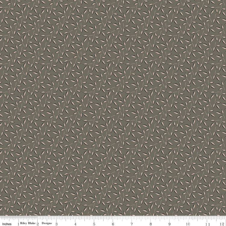 Evergreen Gray fabric with blush-beige leaves, dark gray accents, and winding stems on taupe gray with ruler for scale.