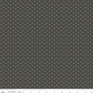 Lottie Gray fabric with tiny cream leaf sprigs and dots in alternating rows on a dark warm gray background with ruler for scale.